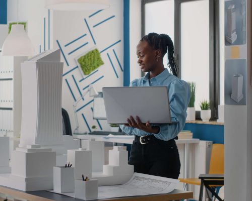 woman-architect-holding-laptop-analyze-building-model-architectural-office-engineer-working-with-computer-maquette-design-construction-structure-urban-project (1)